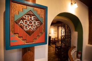 Un cartello che legge la barra di adobe appesa a un muro di The Historic Taos Inn a Taos