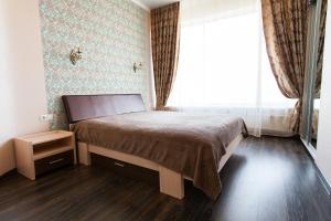 a bedroom with a bed and a large window at Sun City Apart Hotel in Dnipro
