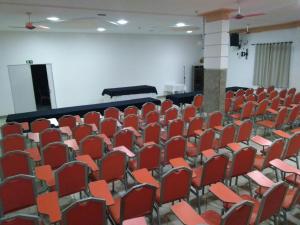 um quarto vazio com cadeiras vermelhas e um palco em Esplendor Palace Hotel em Vitória da Conquista