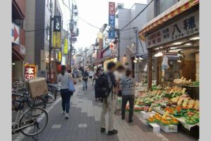 um grupo de pessoas caminhando por um mercado com frutas e legumes em Dwell Urban 6C em Tóquio
