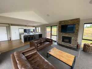 a living room with leather furniture and a fireplace at Starview 88 in Lake Tekapo