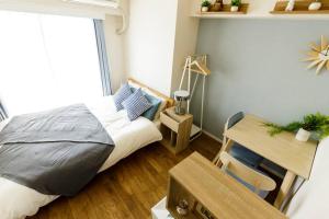 a bedroom with a bed and a desk and a window at Dwell Urban 4C in Tokyo