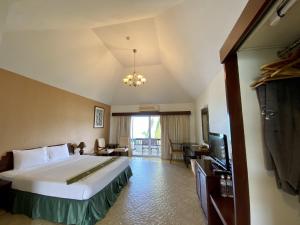 a hotel room with a bed and a television at Golden Pine Beach Resort in Pran Buri