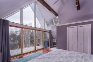 - une chambre avec un lit et une grande fenêtre dans l'établissement Classic Stowe Ski Chalet chalet, à Stowe