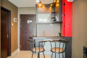 a kitchen with two bar stools and a counter at Modern Design 1BR Apartment at Brooklyn Alam Sutera By Travelio in Tangerang