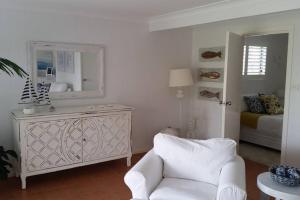 a living room with a white chair and a mirror at Sapphire Beach Pet Friendly Beach 5 minute walk in Sapphire Beach