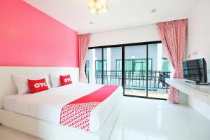 a bedroom with a bed with a pink wall at Tina Boutique Resort in Thalang