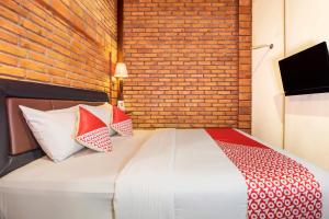 1 dormitorio con 1 cama con pared de ladrillo en Super OYO 3118 Maxi Budget, en Kuta