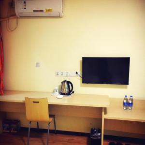 a room with a desk with a television on the wall at 7Days Inn Guiyang Jinyang Century City Shopping Center in Guiyang