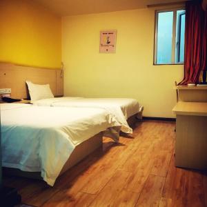 um quarto com 2 camas e piso em madeira em 7Days Inn Guiyang Jinyang Century City Shopping Center em Guiyang