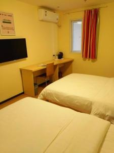 a room with two beds and a desk with a computer at 7Days Inn Guiyang Ergezhai in Guiyang