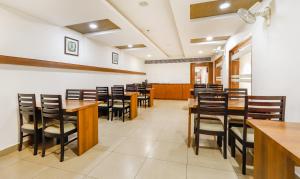 una sala da pranzo con tavoli e sedie in legno di The Mount City Near US Consulate a Chennai Altre 27 foto