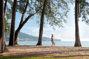 a woman walking on a beach near the water at InterContinental Phuket Resort by IHG in Kamala Beach