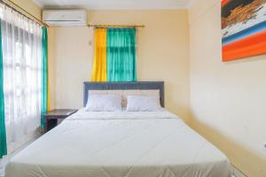 a bedroom with a white bed with a window at Mahendra Beach Inn in Kuta