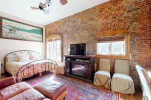 1 dormitorio con pared de ladrillo, cama y TV en Jarvis #303, en Durango