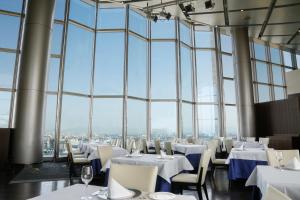 a restaurant with white tables and chairs and large windows at Hotel Keihan Universal Tower in Osaka