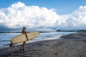 a woman standing on the beach holding a surfboard at Kudakalliya Beach House in Arugam Bay +28 photos