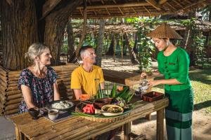 um grupo de pessoas sentadas à mesa com comida em Eskala Hotels and Resorts em Ngwesaung