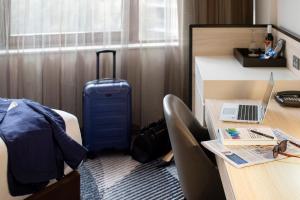 a room with a bed and a desk with a laptop on it at Novotel Sydney Parramatta in Sydney