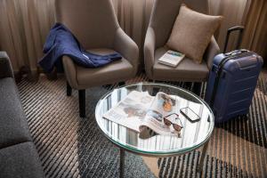 a living room with two chairs and a glass table at Novotel Sydney Parramatta in Sydney