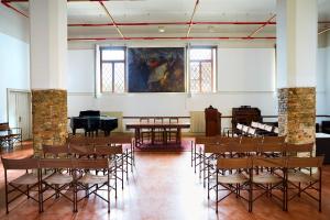 uma sala com mesas e cadeiras e um piano em Ostello AMDG em Veneza