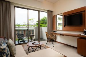 a living room with a couch and a desk with a television at MERUSAKA Nusa Dua in Nusa Dua