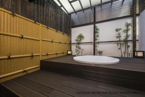 ein Bad mit einer großen Badewanne in einem Zimmer mit Pflanzen in der Unterkunft Shiki Suites - Kyoto Umekoji in Kyoto