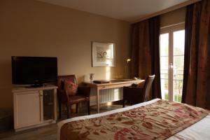 ein Hotelzimmer mit einem Bett, einem Schreibtisch und einem TV in der Unterkunft Ampervilla Hotel in Fahrenzhausen