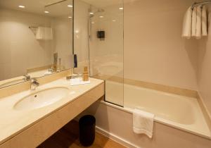 
a bathroom with a tub, sink and mirror at Hotel Eden Park by Brava Hoteles in Riudellots de la Selva
