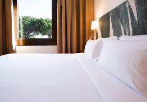 two white beds in a hotel room with a window at Hotel Eden Park by Brava Hoteles in Riudellots de la Selva
