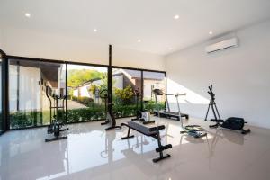 a gym with cardio equipment in a room with large windows at Thames Tara Pool Villa Rawai Phuket - SHA Extra Plus in Rawai Beach