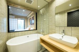 a bathroom with a tub and a sink and a mirror at Shiki Suites - Kyoto Umekoji in Kyoto