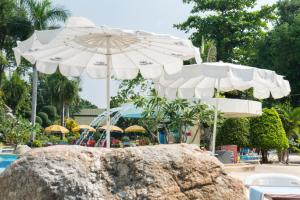 een groep parasols naast een zwembad bij Grand Jomtien Palace Hotel - SHA Extra Plus in Jomtien Beach