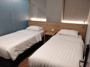 two beds in a small room with white sheets at Hotel Marina Airport Semarang in Semarang