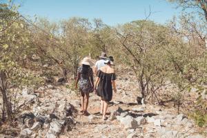 un grupo de tres personas caminando por un camino rocoso en Etosha Safari Campsite, en Outjo