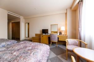 Habitación de hotel con cama, mesa y sillas en Fukuno Town Hotel A・Mieux, en Nanto