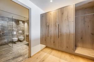 een badkamer met houten lambrisering, een douche en een toilet bij Almhotel Glieshof in Malles Venosta