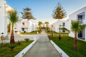 a walkway in front of a white building with palm trees at Solimar White Pearl - Adults Only in Kolymvari