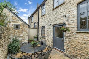 a patio with a table and chairs in front of a building at Oxfordshire Living - The Bowler Hat Cottage - Woodstock in Woodstock