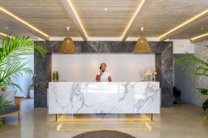 a woman standing behind a marble counter in a lobby at Solimar White Pearl - Adults Only in Kolymvari