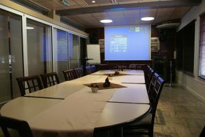 a conference room with tables and chairs and a large screen at Logis Hôtel Mediterranee in Port-la-Nouvelle