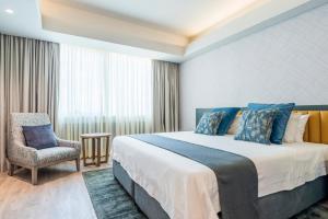 una habitación de hotel con una cama grande y una silla en Rainbow Towers Hotel & Conference Centre en Harare