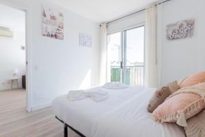 a white bedroom with a bed and a large window at matarolux18 in Mataró