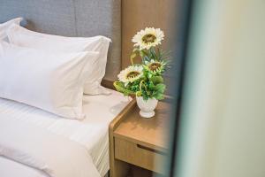 a bed with a vase with flowers on a night stand at GRAND FLORA HOTEL in Melaka