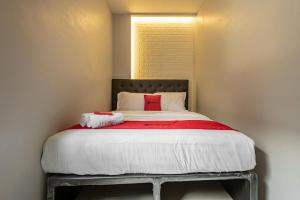 a bed in a small room with a red pillow at RedDoorz near Tanjung Duren 2 in Jakarta