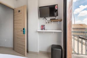 a room with a tv on the wall next to a window at RedDoorz near Tanjung Duren 2 in Jakarta