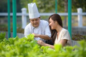 a man and a woman in a chefs hat looking at lettuce at Dusit Thani Hua Hin in Cha Am