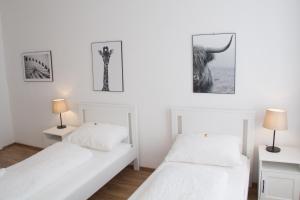 duas camas num quarto branco com fotografias na parede em Vienna4you App 20 you are welcome em Viena