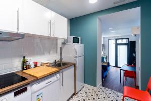 a kitchen with a white refrigerator and a blue wall at Housingleón - Albergue Turístico Nama Hostel in León