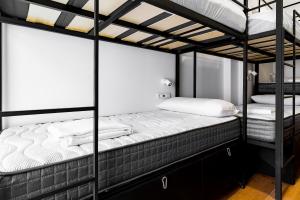 een slaapkamer met 2 stapelbedden met witte lakens bij Housingleón - Albergue Turístico Nama Hostel in León